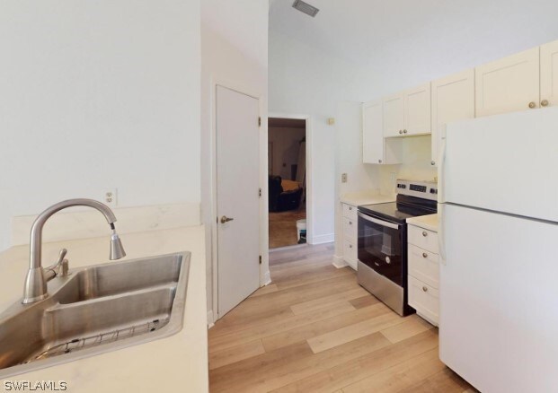 kitchen with white cabinetry, white refrigerator, sink, light hardwood / wood-style floors, and stainless steel electric range oven