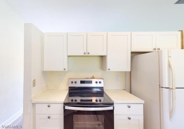 kitchen featuring white cabinetry, stainless steel electric stove, and white refrigerator