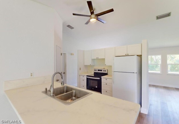 kitchen featuring hardwood / wood-style floors, sink, electric range, white fridge, and ceiling fan