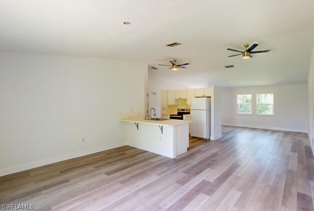 kitchen with light wood-type flooring, kitchen peninsula, ceiling fan, range with electric stovetop, and white refrigerator