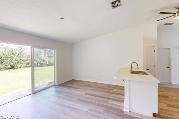 interior space with sink, ceiling fan, lofted ceiling, and light hardwood / wood-style floors