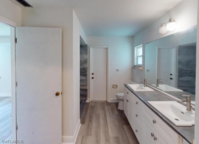 bathroom with toilet, hardwood / wood-style flooring, and double vanity