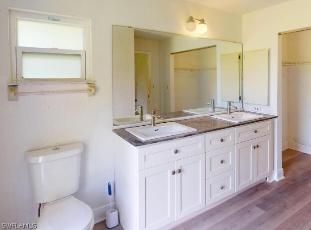 bathroom with toilet, hardwood / wood-style flooring, and double vanity