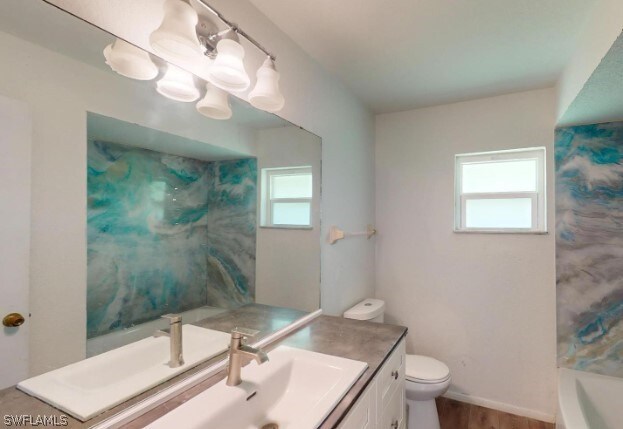 bathroom featuring vanity, toilet, a wealth of natural light, and hardwood / wood-style flooring