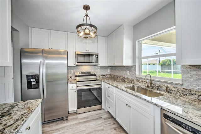 kitchen with sink, tasteful backsplash, appliances with stainless steel finishes, pendant lighting, and white cabinets