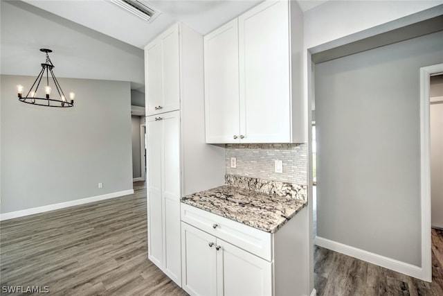 kitchen featuring white cabinets, decorative backsplash, dark hardwood / wood-style flooring, and light stone counters