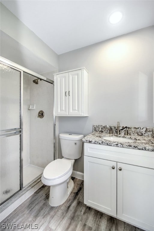 bathroom with vanity, hardwood / wood-style flooring, toilet, and a shower with shower door