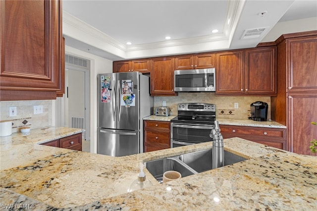 kitchen featuring decorative backsplash, appliances with stainless steel finishes, light stone counters, and a raised ceiling