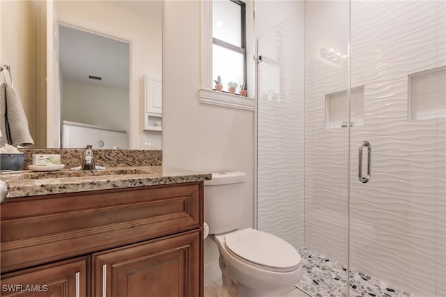 bathroom featuring toilet, a shower with door, and vanity