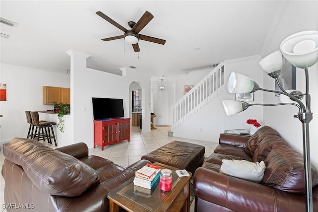 tiled living room with ceiling fan, crown molding, and decorative columns