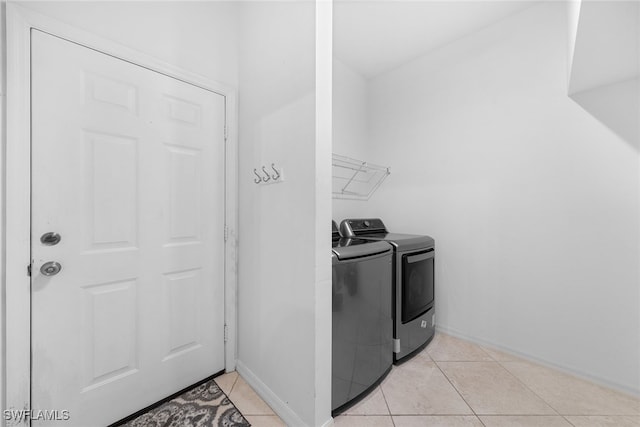 clothes washing area featuring light tile patterned floors and washing machine and dryer