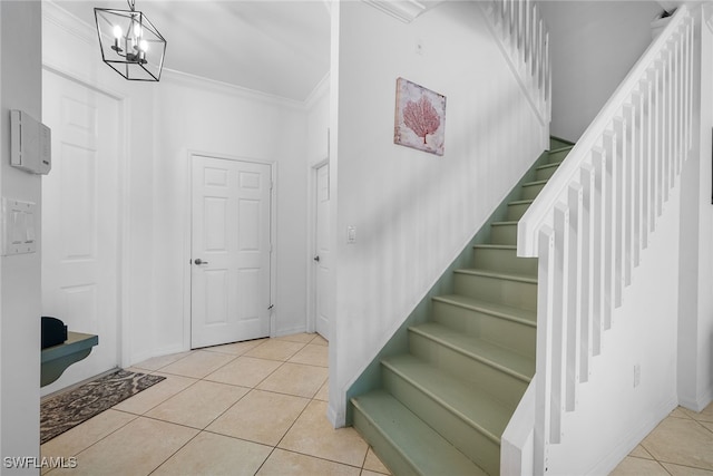 tiled foyer with ornamental molding and a notable chandelier