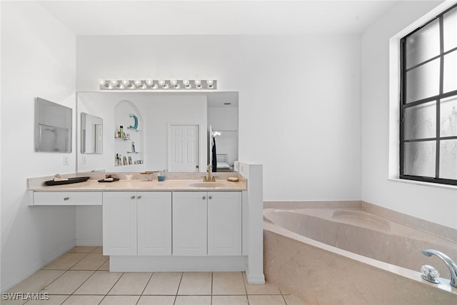 bathroom with tile patterned flooring, vanity, and a relaxing tiled tub