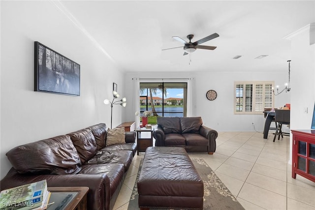 living room featuring ornamental molding, light tile patterned flooring, visible vents, and ceiling fan with notable chandelier