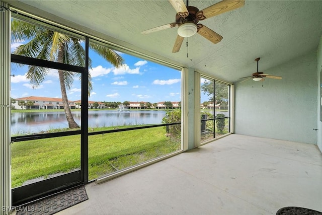 unfurnished sunroom featuring a ceiling fan and a water view