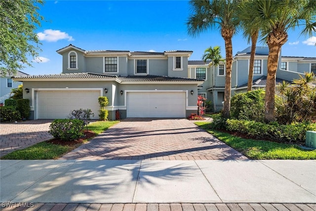 view of front of home with stucco siding, decorative driveway, a tiled roof, and an attached garage