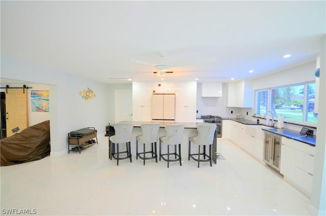 kitchen with a kitchen breakfast bar, a spacious island, white cabinets, a barn door, and white fridge