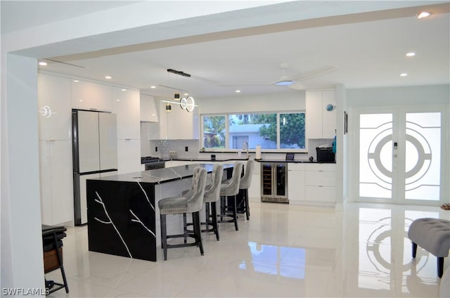 kitchen featuring fridge, a center island, white cabinets, decorative light fixtures, and beverage cooler