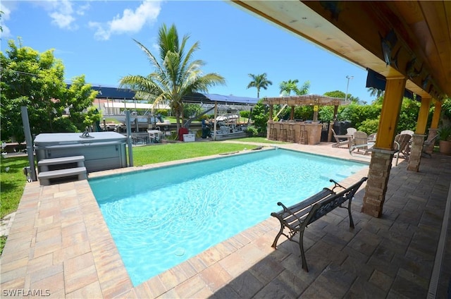 view of swimming pool with a hot tub, a patio area, and a bar