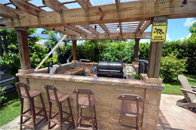 view of patio with exterior bar, a grill, an outdoor kitchen, and a pergola