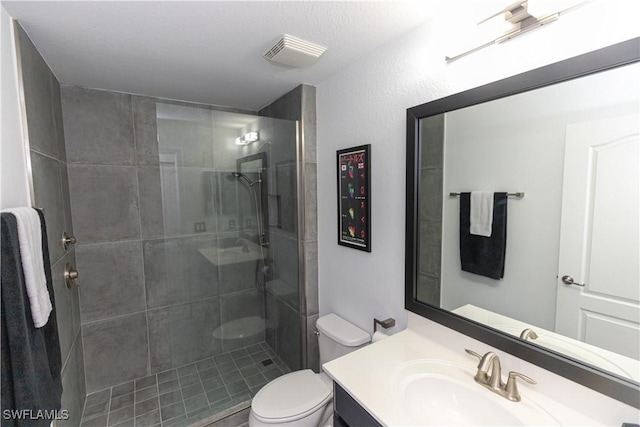 full bathroom featuring toilet, vanity, visible vents, and a tile shower