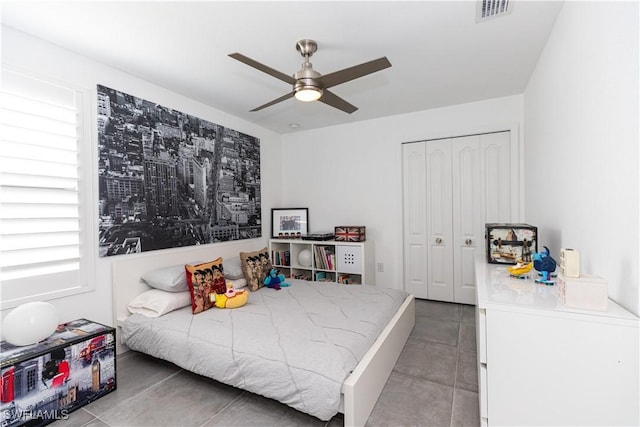 tiled bedroom with ceiling fan and a closet