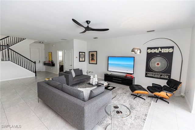 living area featuring ceiling fan, stairway, visible vents, and baseboards