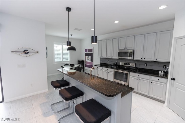 kitchen with white cabinets, a breakfast bar area, stainless steel appliances, and pendant lighting