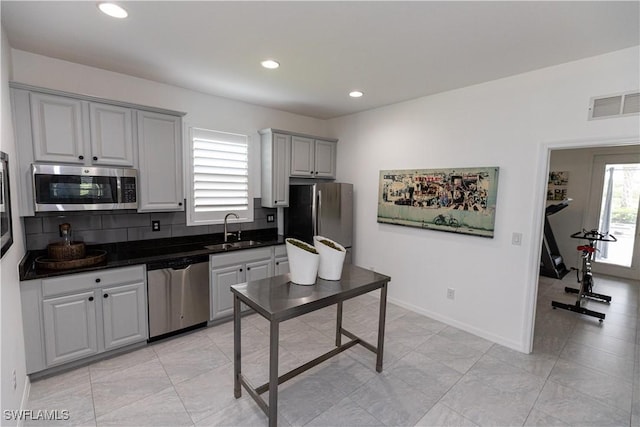 kitchen with stainless steel appliances, a sink, visible vents, gray cabinets, and dark countertops