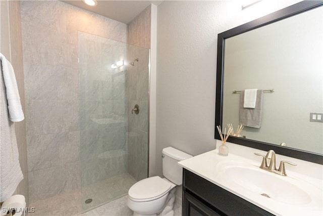 bathroom featuring a tile shower, vanity, and toilet