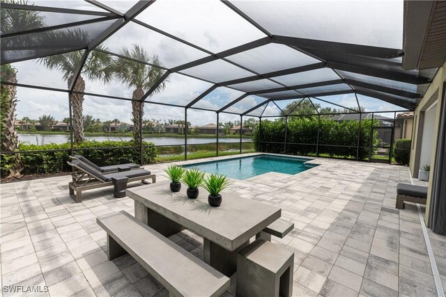 view of swimming pool with glass enclosure, a patio area, and a water view