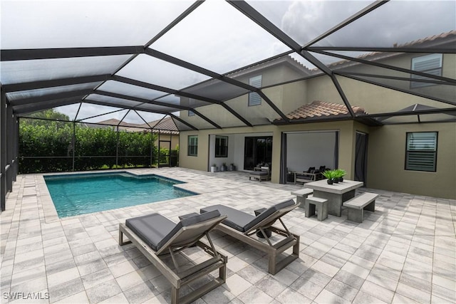 view of pool with an outdoor hangout area, a patio area, and glass enclosure