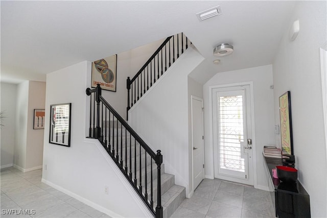 foyer featuring stairway, baseboards, and visible vents