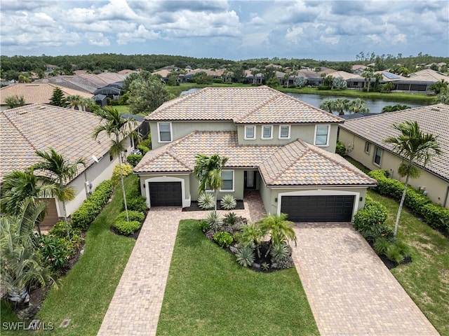 view of front of house with decorative driveway, a water view, an attached garage, a residential view, and a front lawn