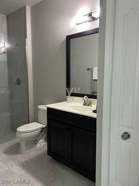 bathroom featuring a textured wall, vanity, toilet, and a walk in shower