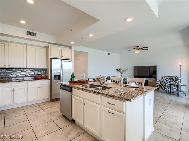 kitchen featuring ceiling fan, stainless steel appliances, stone counters, sink, and light tile patterned floors