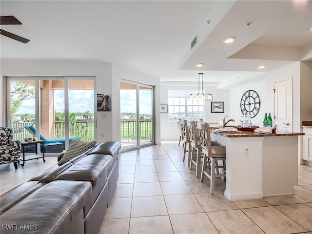 kitchen featuring pendant lighting, dark stone counters, a breakfast bar, and light tile patterned floors