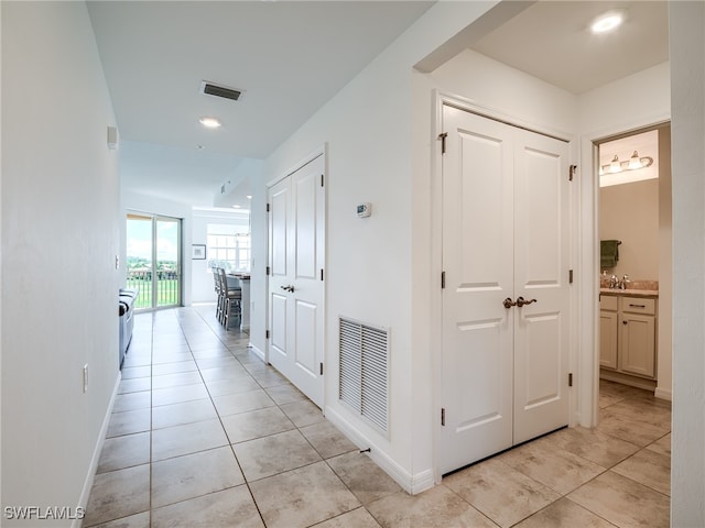 corridor featuring sink and light tile patterned floors