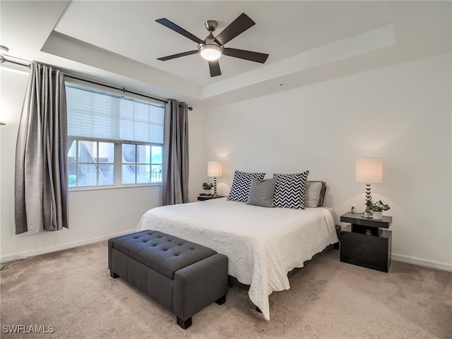 carpeted bedroom featuring ceiling fan and a tray ceiling