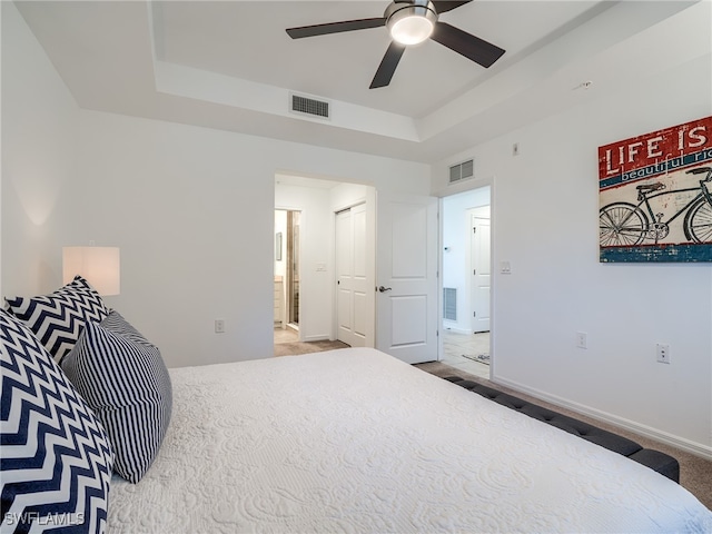 bedroom with connected bathroom, ceiling fan, a raised ceiling, and tile patterned floors