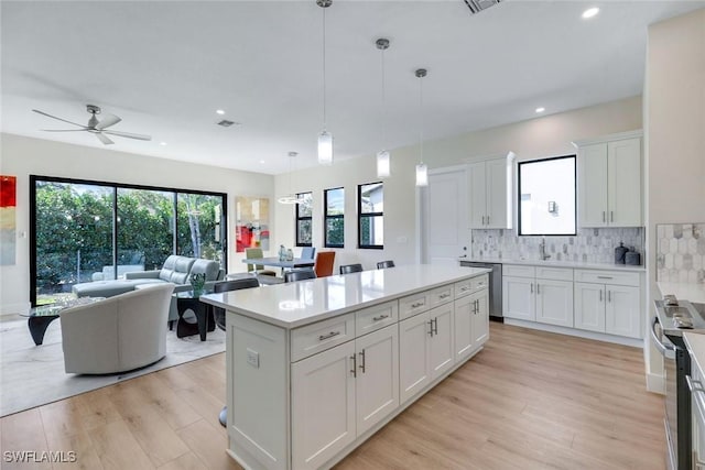 kitchen featuring stainless steel appliances, light wood-style flooring, decorative backsplash, and light countertops