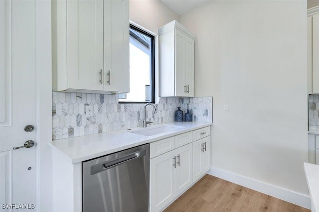 kitchen featuring a sink, light countertops, white cabinets, stainless steel dishwasher, and tasteful backsplash