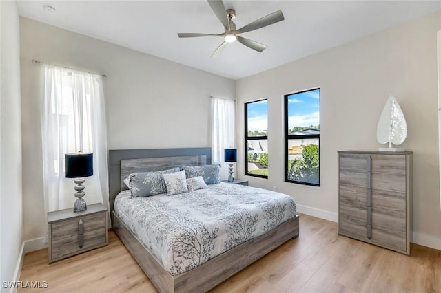 bedroom with a ceiling fan, baseboards, and light wood finished floors