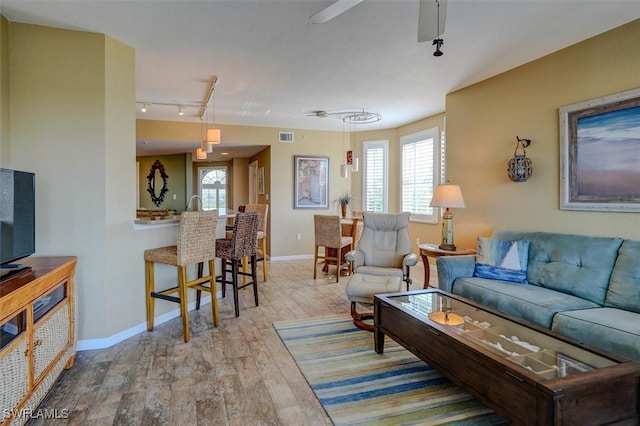 living room with ceiling fan, light wood-type flooring, and a wealth of natural light