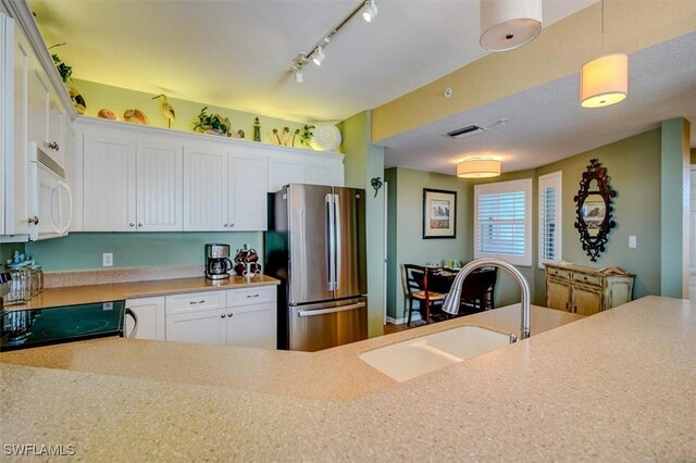 kitchen with sink, stainless steel fridge, white cabinetry, electric range, and decorative light fixtures