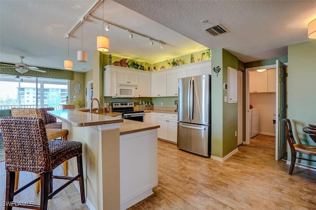 kitchen featuring pendant lighting, white cabinets, a kitchen bar, kitchen peninsula, and stainless steel appliances