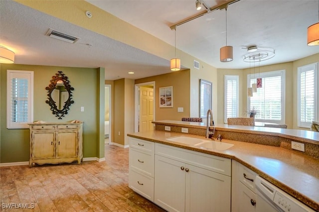 kitchen featuring dishwasher, sink, white cabinets, hanging light fixtures, and light hardwood / wood-style floors