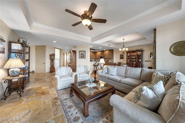 living room featuring crown molding, a tray ceiling, and ceiling fan with notable chandelier