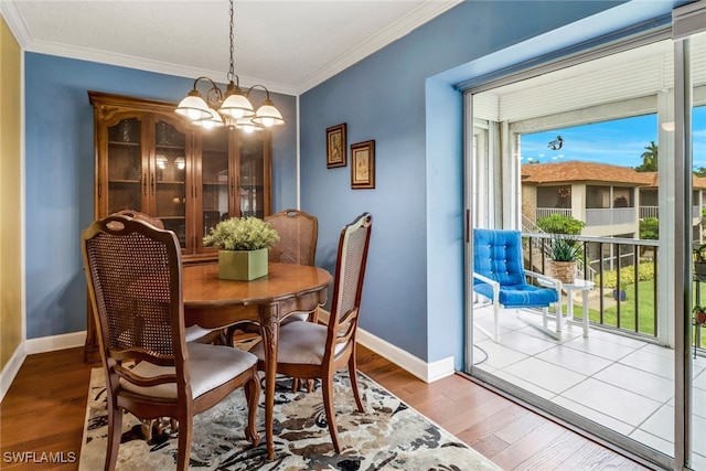 dining area with crown molding, wood-type flooring, and a notable chandelier