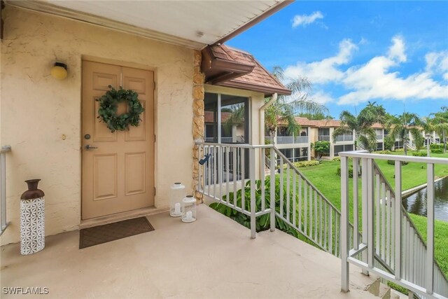 doorway to property featuring a water view and a lawn